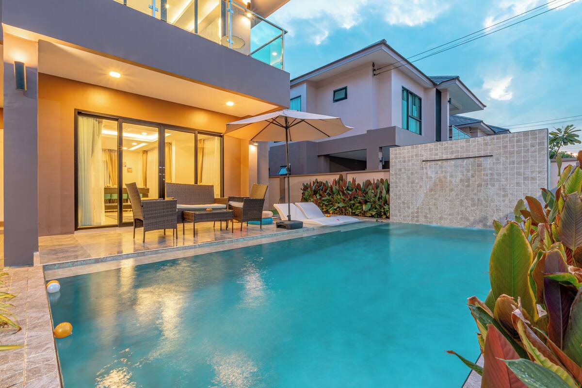 Un área de piscina moderna con un porche de cristal, mobiliario exterior y vistas despejadas a la piscina.