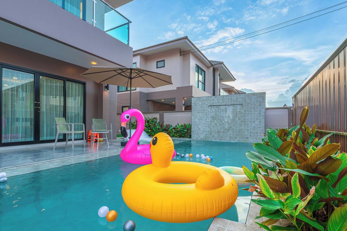 Un área de piscina con flamencos hinchables y un flotador de flamenco amarillo.
