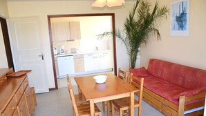 A compact living space with a kitchenette, a dining table with chairs, a sofa, and a large plant. - Beautiful T3 apartment with balcony and magnificent view (Font-Romeu-Odeillo-Via)