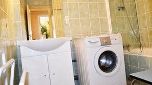 A compact bathroom with a washing machine, a sink, and a shower. - Beautiful T3 apartment with balcony and magnificent view (Font-Romeu-Odeillo-Via)