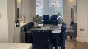 Comedor con una mesa preparada para cuatro, una araña y vista a un edificio de ladrillo por la ventana.