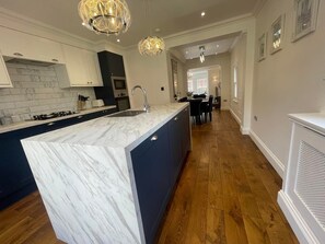 Kitchen features a large island with a sink and oven, pendant lights, and hardwood flooring.