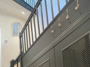 Staircase leads to an upper floor with a classic, arched window and decorative panel.