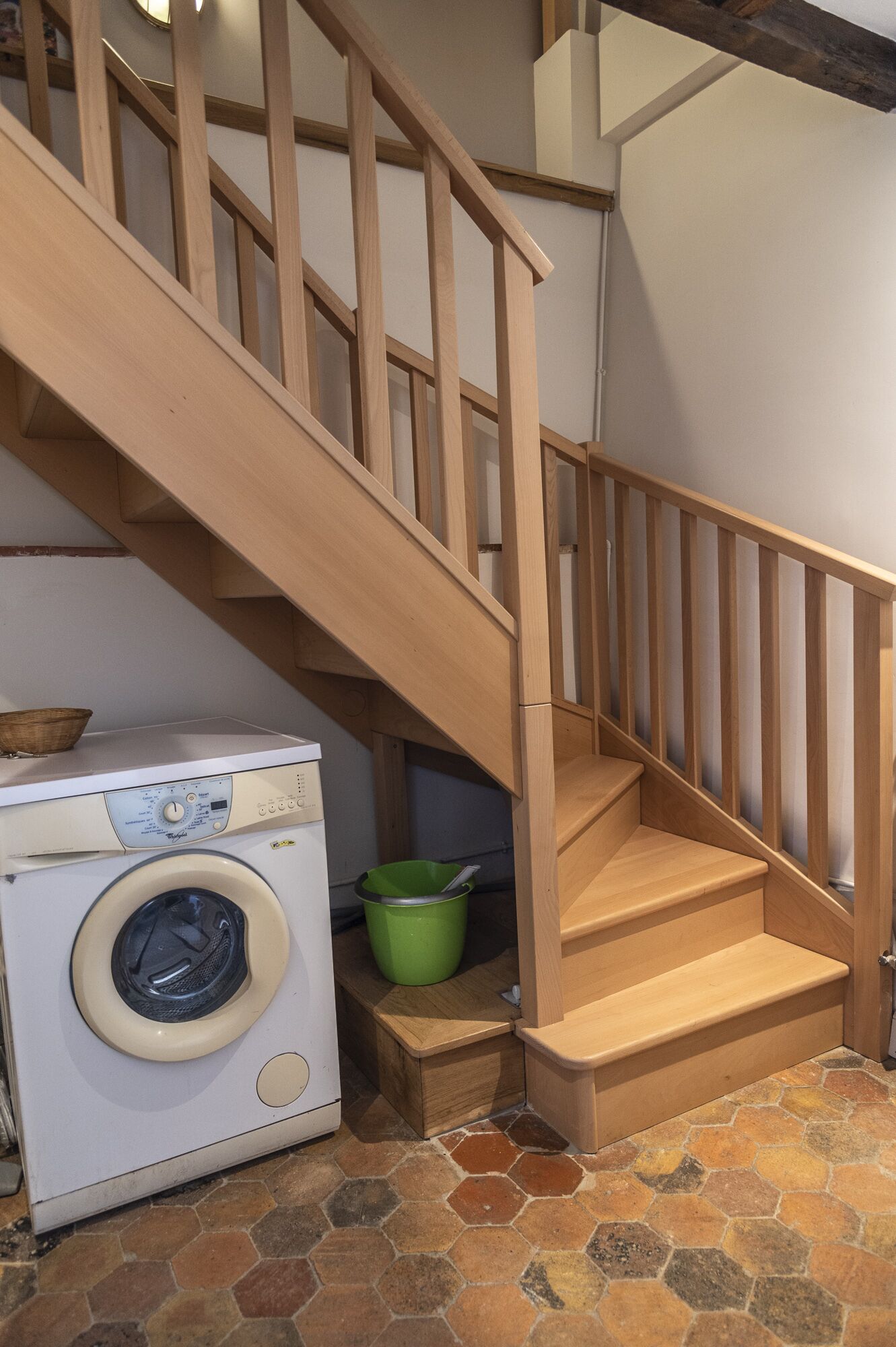 Un espace dédié à la lessive, avec un lave-linge et un seau vert.