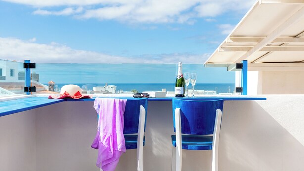 Un balcon avec une table dressée pour deux personnes, offrant une vue sur la côte.
