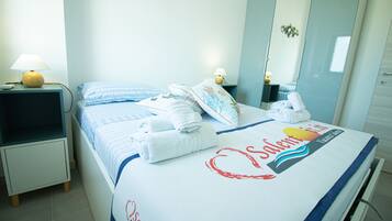 A neatly made bed with blue and white bedding, two bedside lamps, and a mirror on the wall.