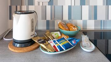Una encimera de cocina con una cafetera, un bol de pan y diferentes productos de snack envasados.