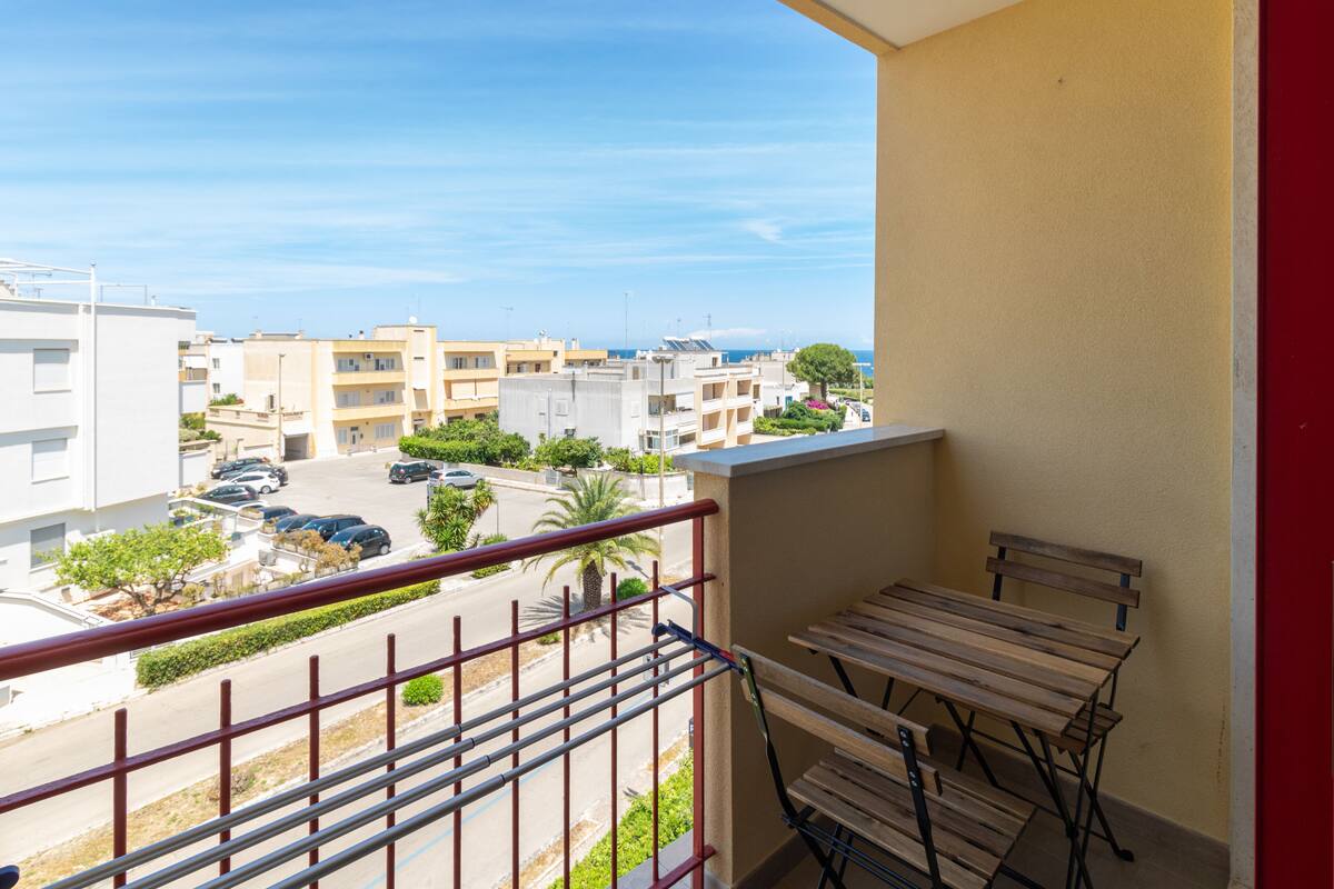 A balcony with a view of a residential area, including buildings and parked cars.