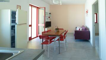 A modern kitchen with a dining area, a TV, and a sofa.