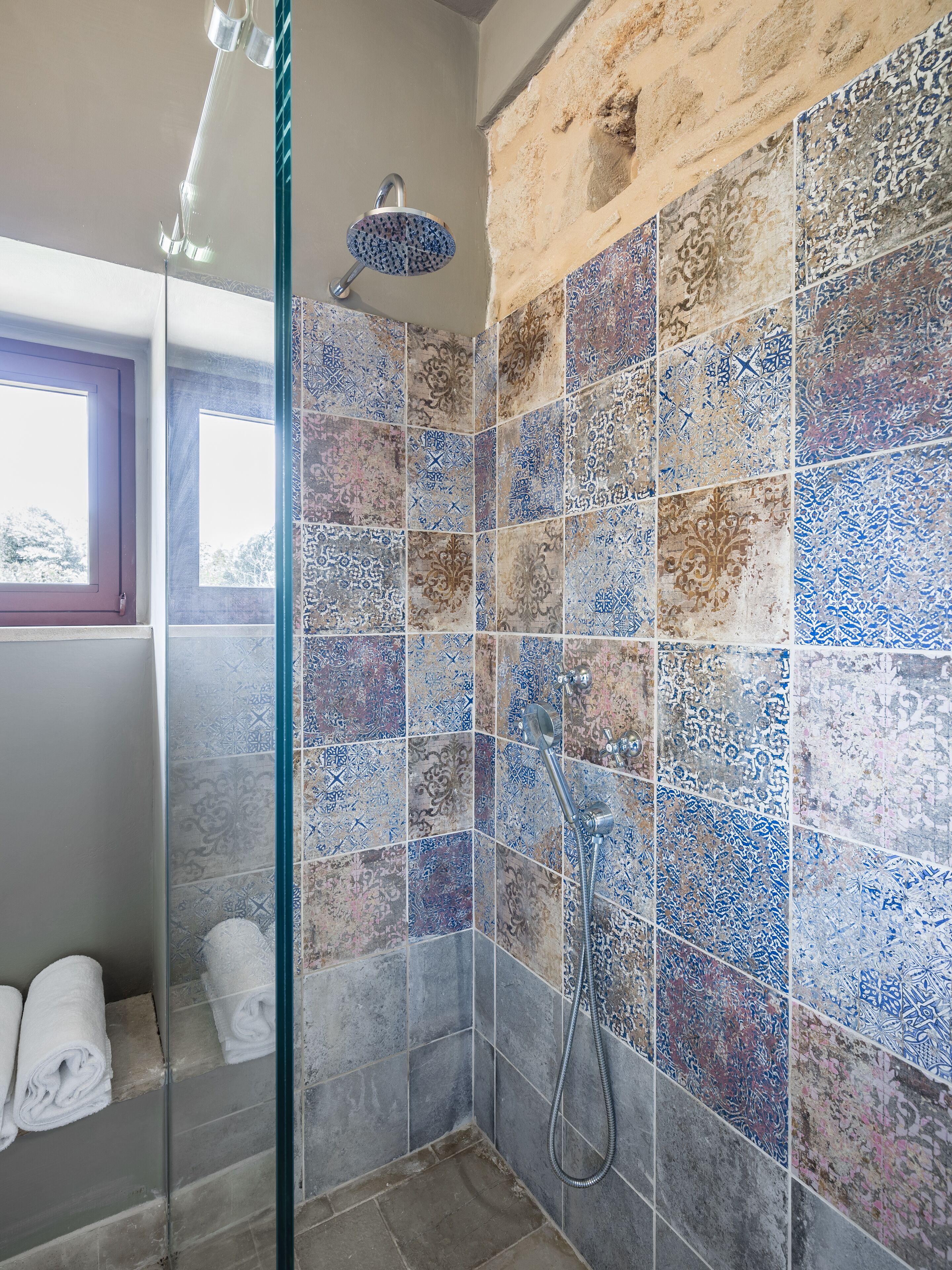A bathroom with a shower, tiled walls, and a window.