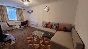 A modern living room with a sofa, coffee table, and a dining area with a table and chairs. - Tastefully Decorated 1 bed Flat Near Abbeywood (Belvedere)