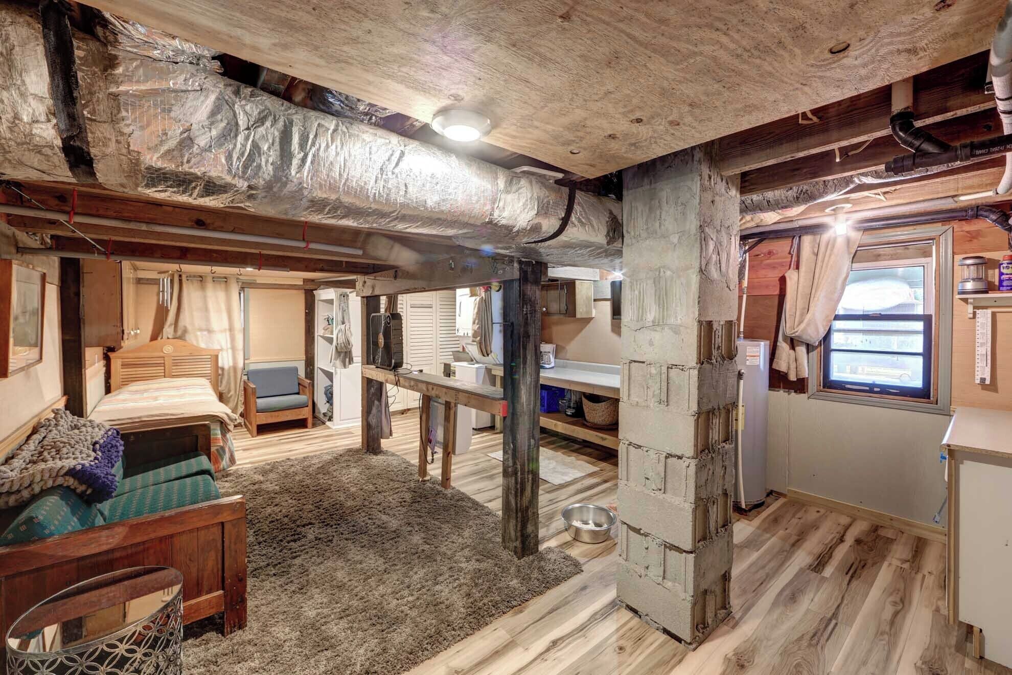 Interior de una cabaña con techo de madera, literas, una pequeña cocina y una ventana con vistas.