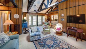 Un salon confortable avec un canapé, des fauteuils, un téléviseur et un grand tapis.