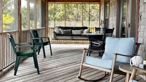A covered porch with wooden flooring, a rocking chair, and a sofa. - Heart's Desire - Ocracoke Island (Ocracoke)