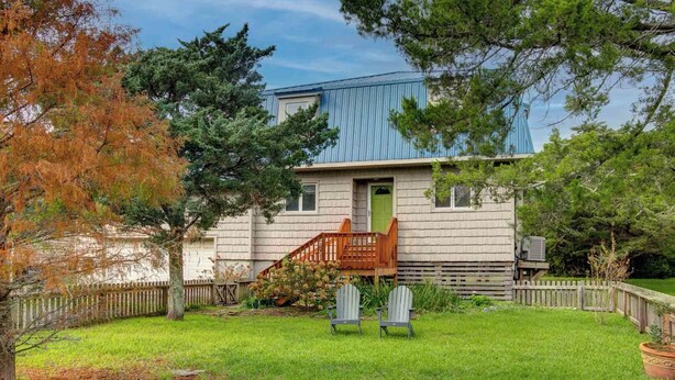 A two-story house with a green door, a wooden staircase, and a fenced yard. - Siren Song - Ocracoke Island (Ocracoke)