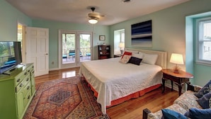 A bedroom with a bed, a television, a dresser, a rug, and a painting on the wall. - Siren Song - Ocracoke Island (Ocracoke)