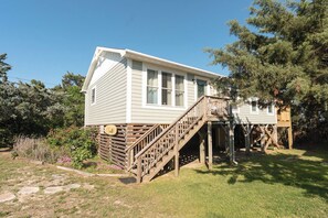 A single-story house with a wooden deck and a staircase leading to a porch.
