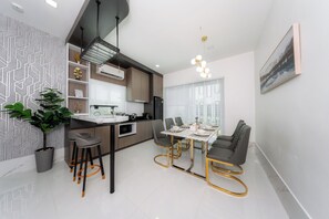 A modern kitchen with a dining area, featuring a central island, bar stools, and a dining table with chairs.
