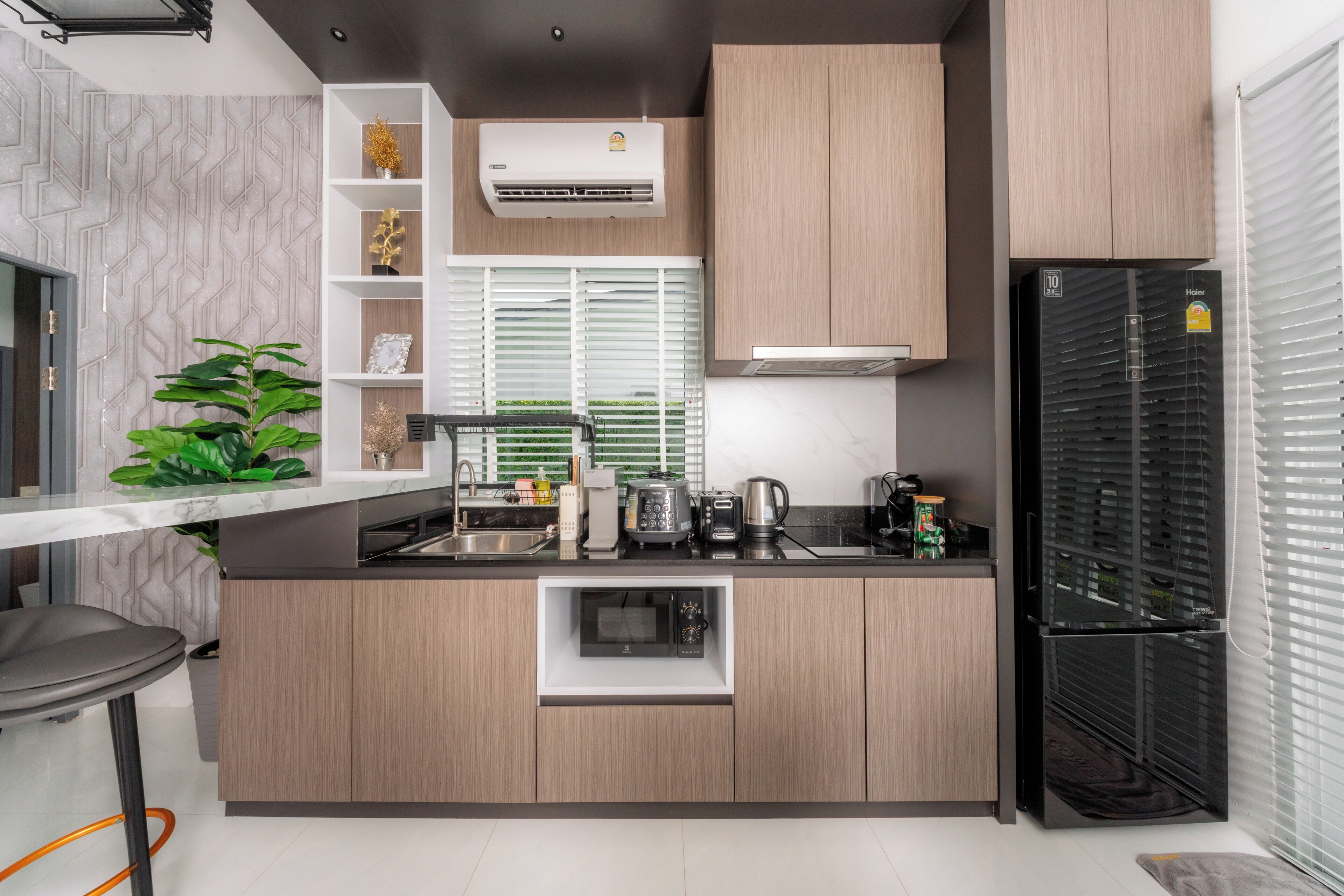A modern kitchen with a built-in microwave, a refrigerator, and a window with blinds.