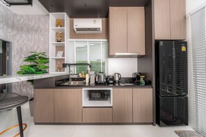 A modern kitchen with a built-in microwave, a refrigerator, and a window with blinds. - Lark Pool Villa Krabi (Krabi)