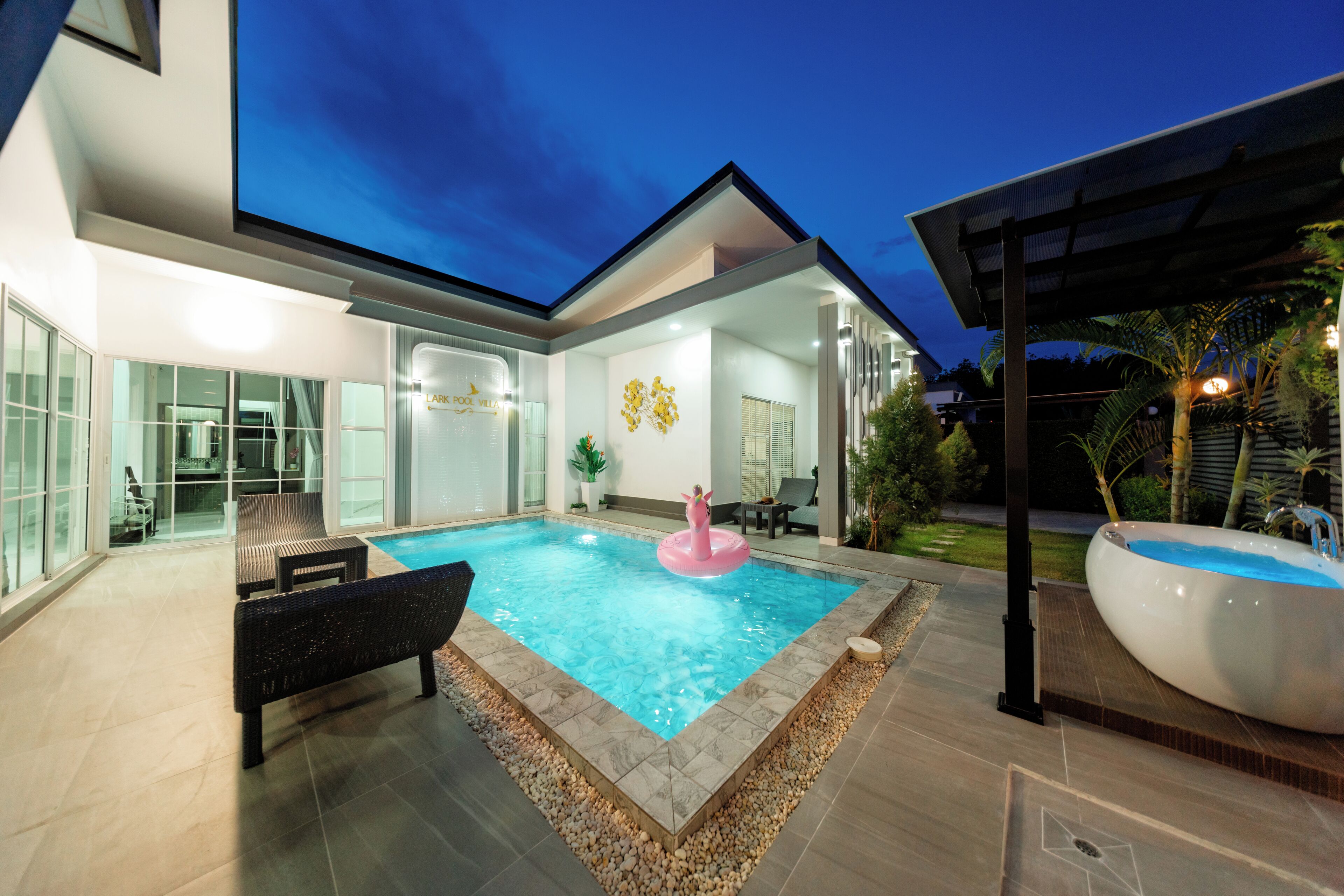 Una casa moderna con piscina, mobiliario exterior y jacuzzi.