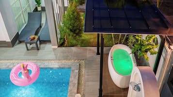 Une piscine avec un flotteur gonflable rose, un jacuzzi avec de l’eau verte et un panneau solaire.