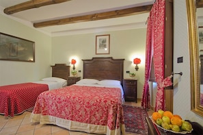 A bedroom with two beds, wooden beams on the ceiling, a framed picture on the wall, and a fruit basket on the floor. - Hotel Ristorante Le Gole (Celano)