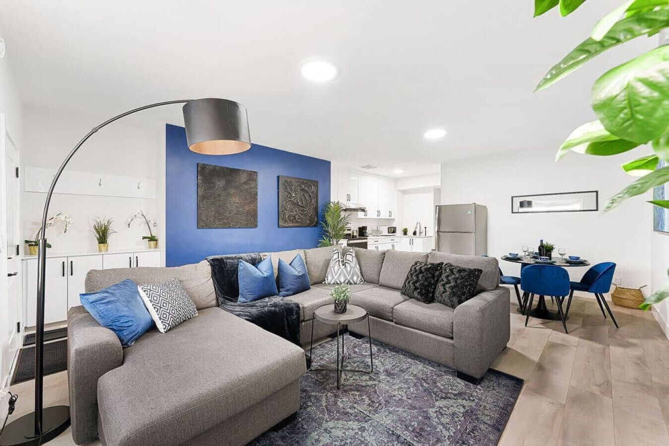 A modern living room with a sofa set, a coffee table, and a dining area with chairs and a table.