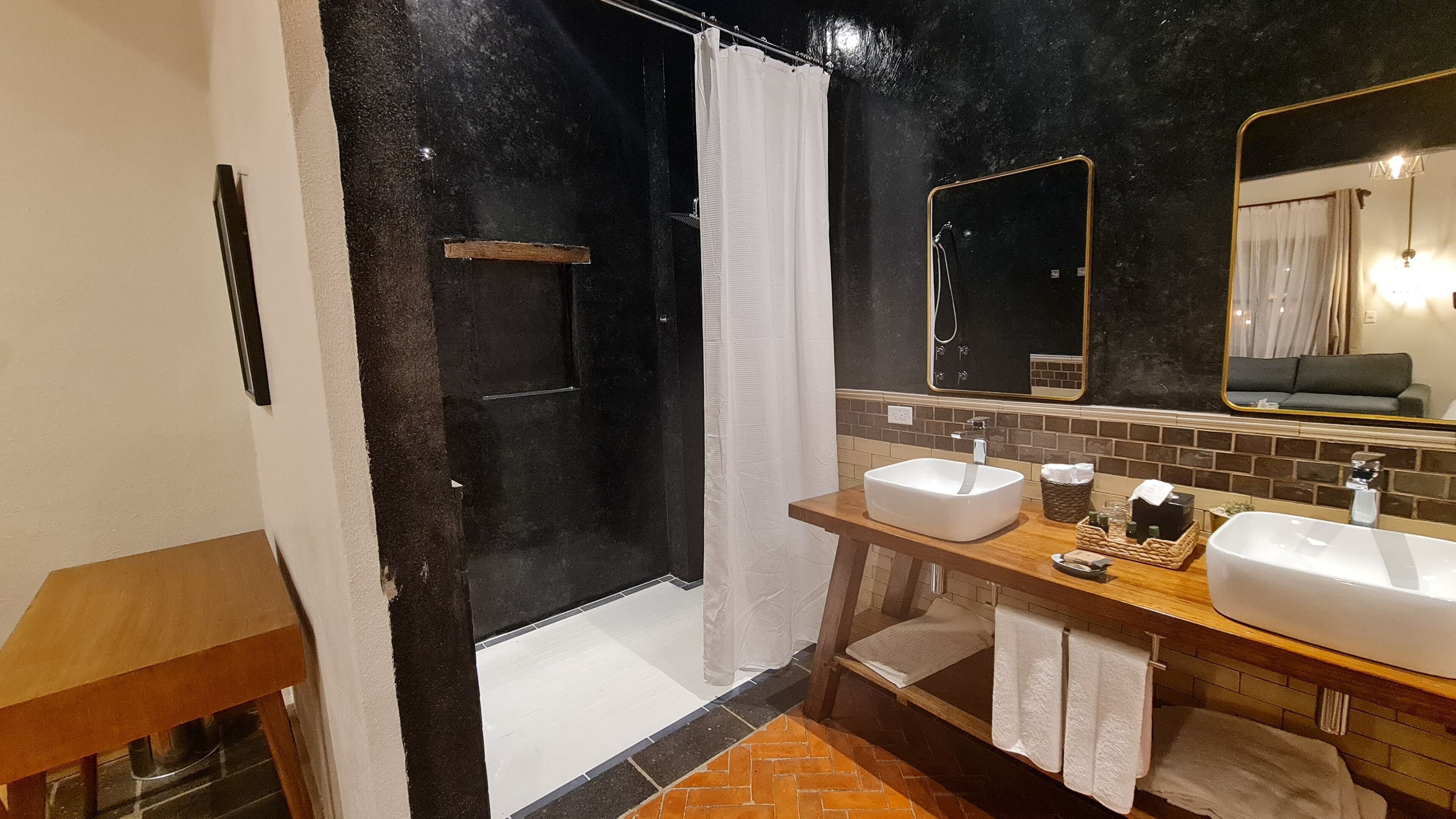 Casa de banho moderna com chuveiro, duas pias e um espelho grande.