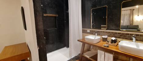 Casa de banho moderna com chuveiro, duas pias e um espelho grande.