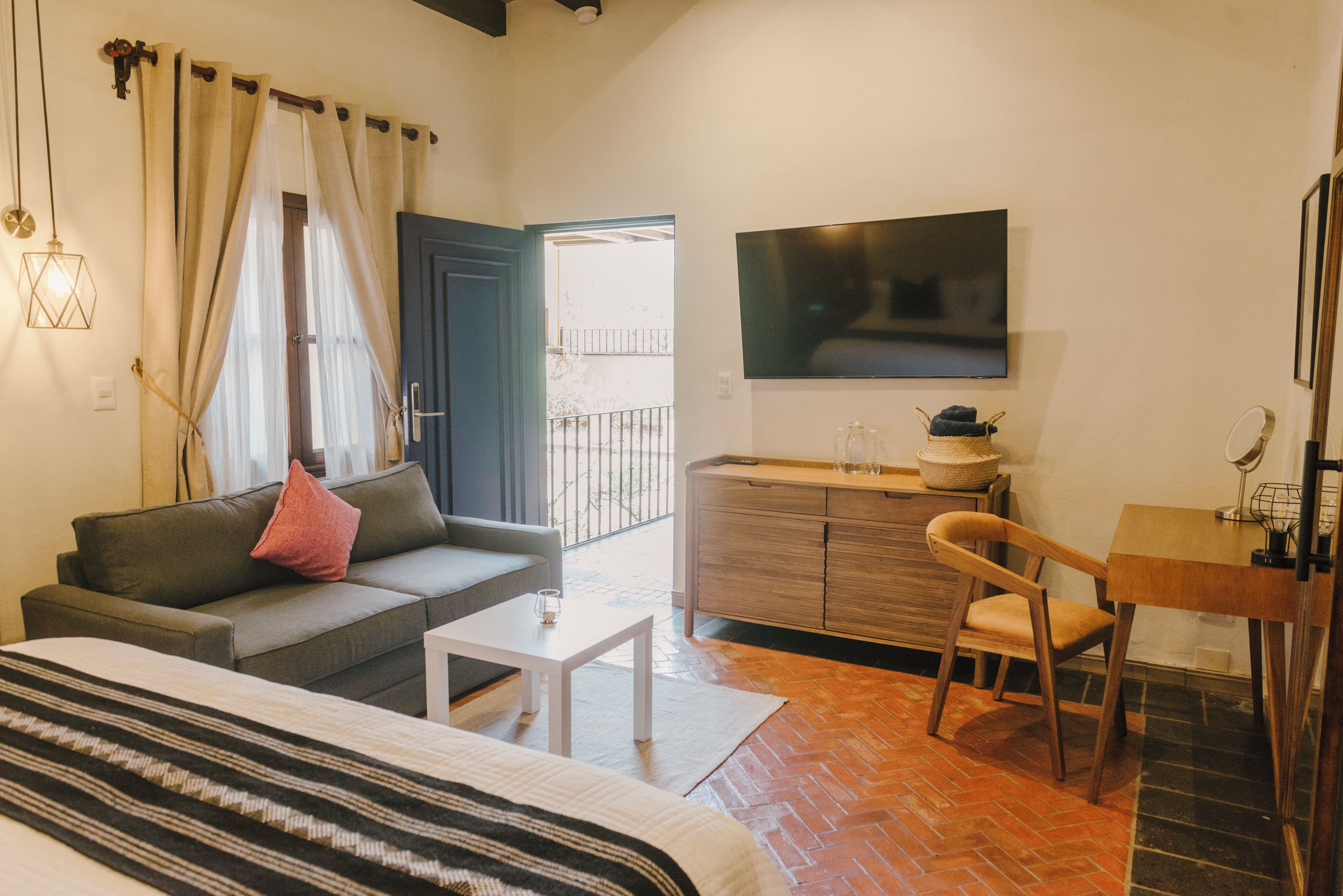 Un dormitorio moderno con cama, sofá, escritorio y televisor.