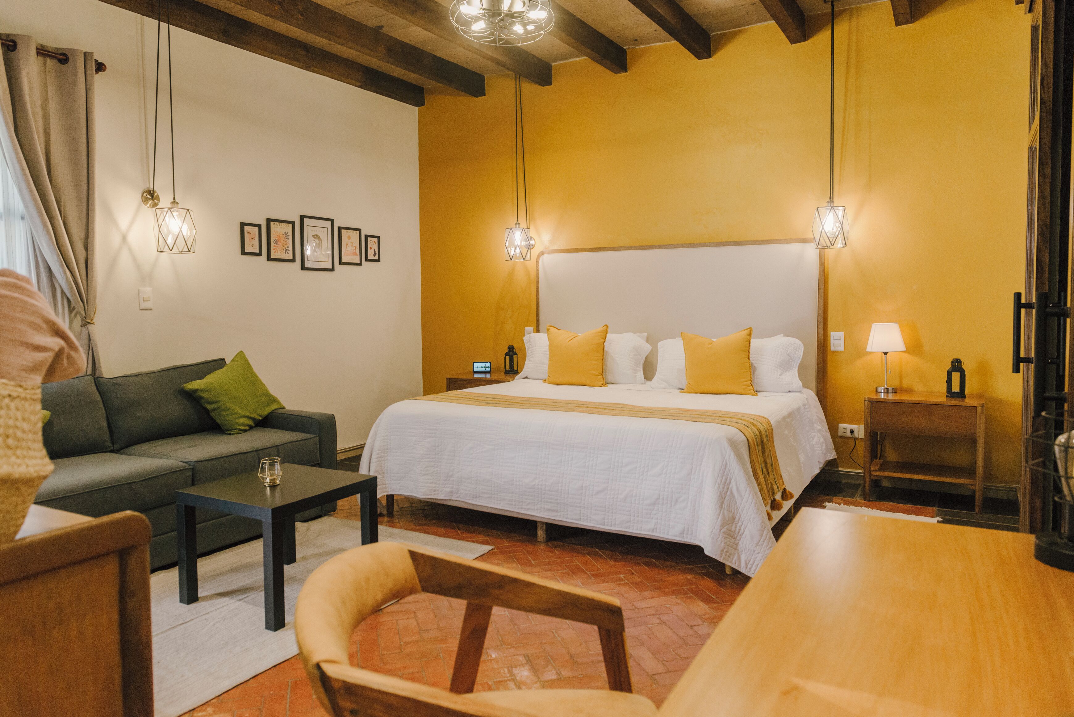 Une chambre d’hôtel avec un lit, un canapé, une table basse et une chaise.