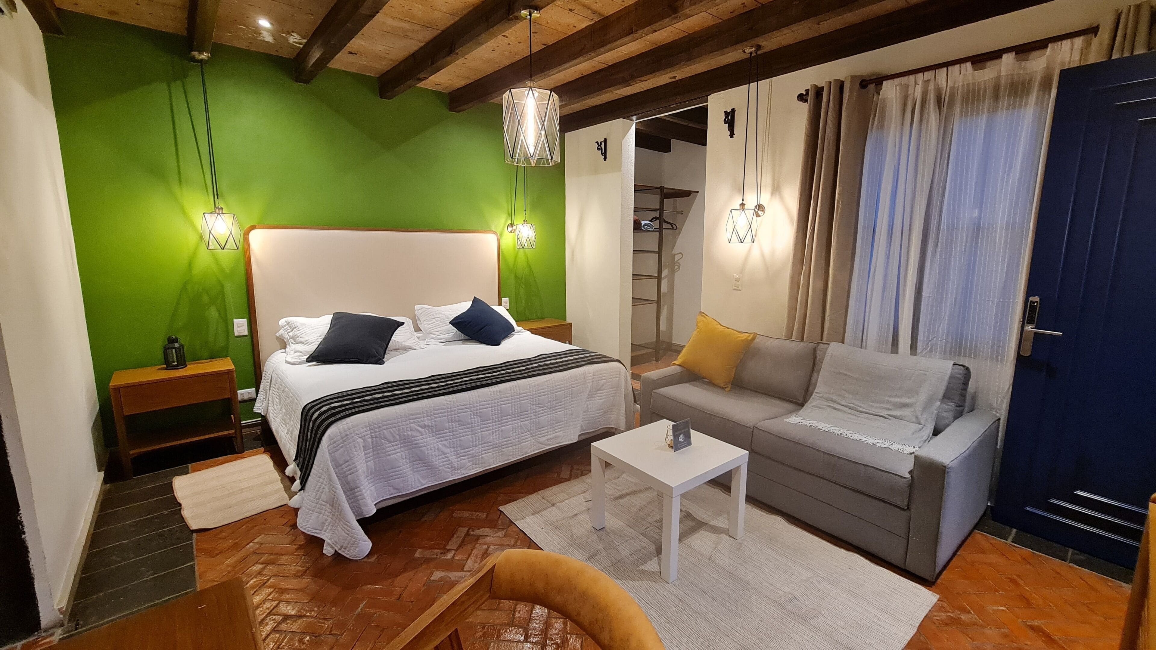 A bedroom with a bed, a sofa, a coffee table, and a nightstand.