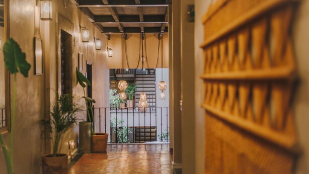 A corridor with wooden flooring, hanging pendant lights, and potted plants. - Agua Santa Hotel Boutique (San Miguel de Allende)