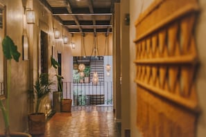 Un pasillo con piso de madera, lámparas colgantes y plantas en macetas.