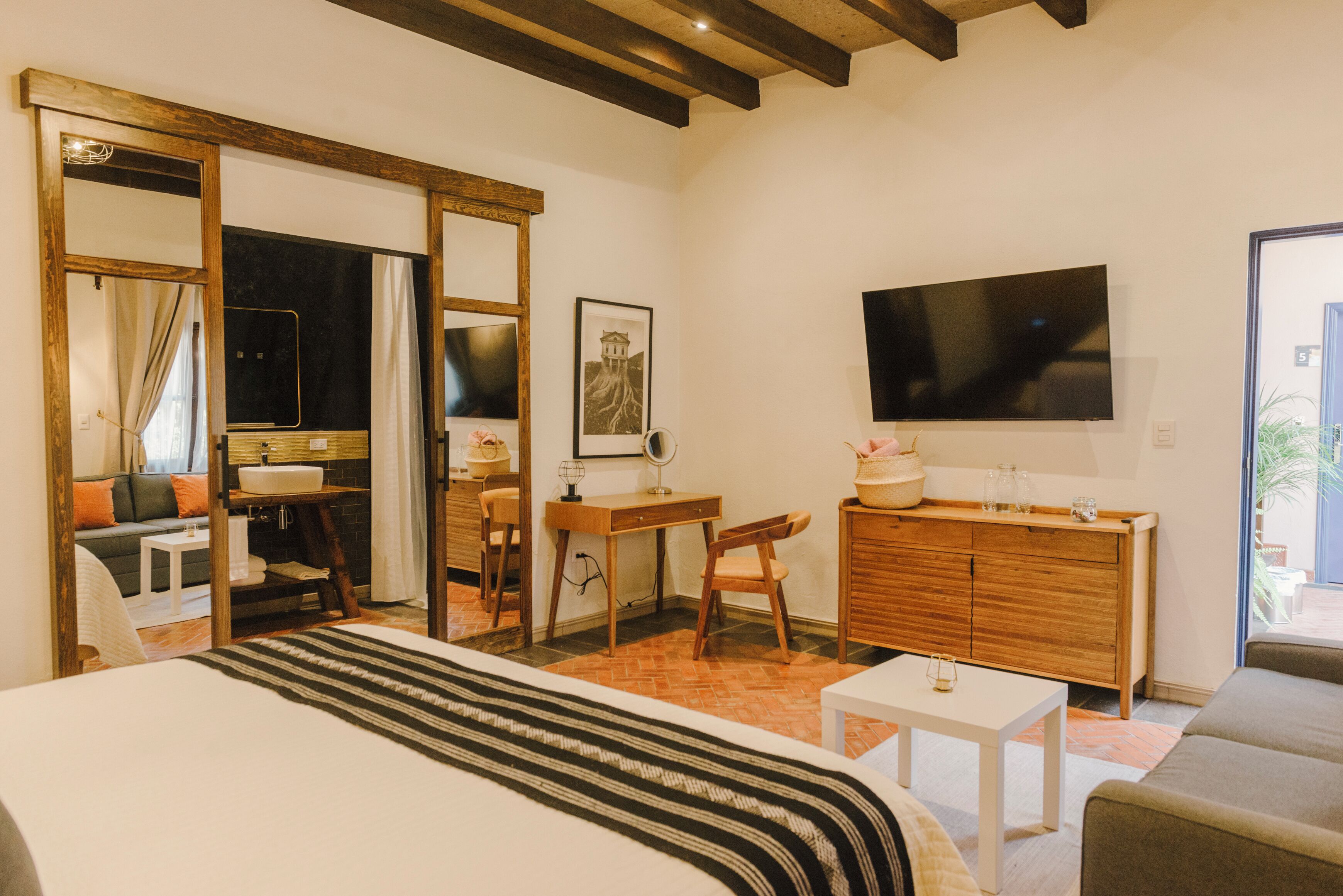 Une chambre d’hôtel avec un lit, un bureau, une chaise, une télévision et un grand miroir.