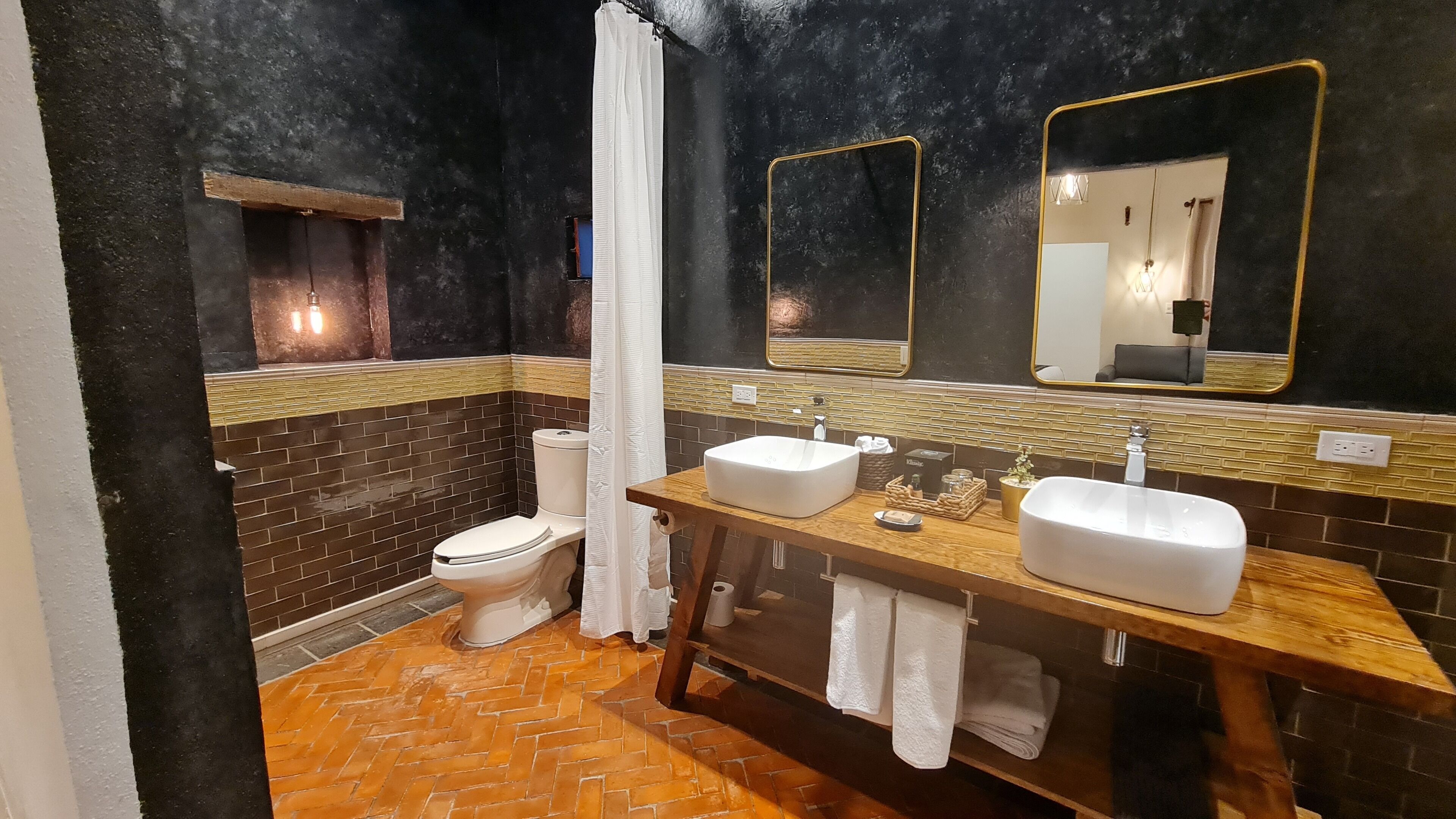 A bathroom with a toilet, two sinks, a mirror, and a shower curtain.