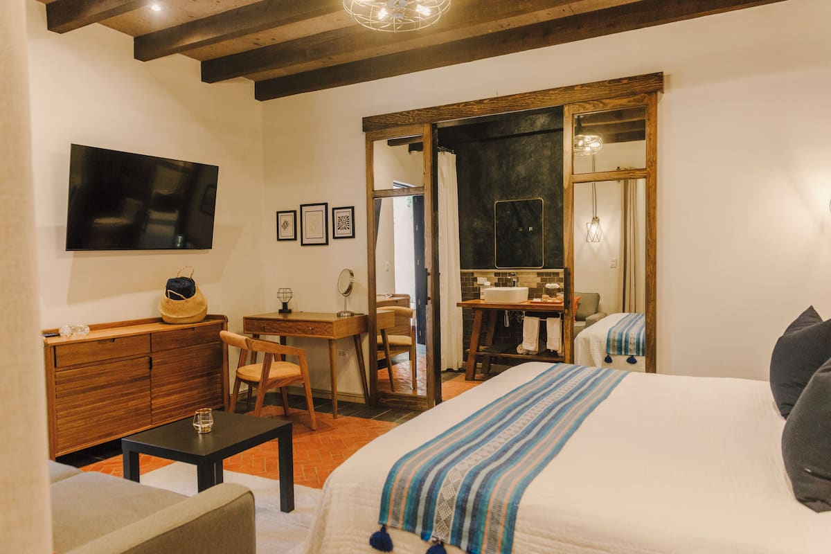 Une chambre à coucher avec un lit, un bureau, une chaise, une télévision et un miroir.