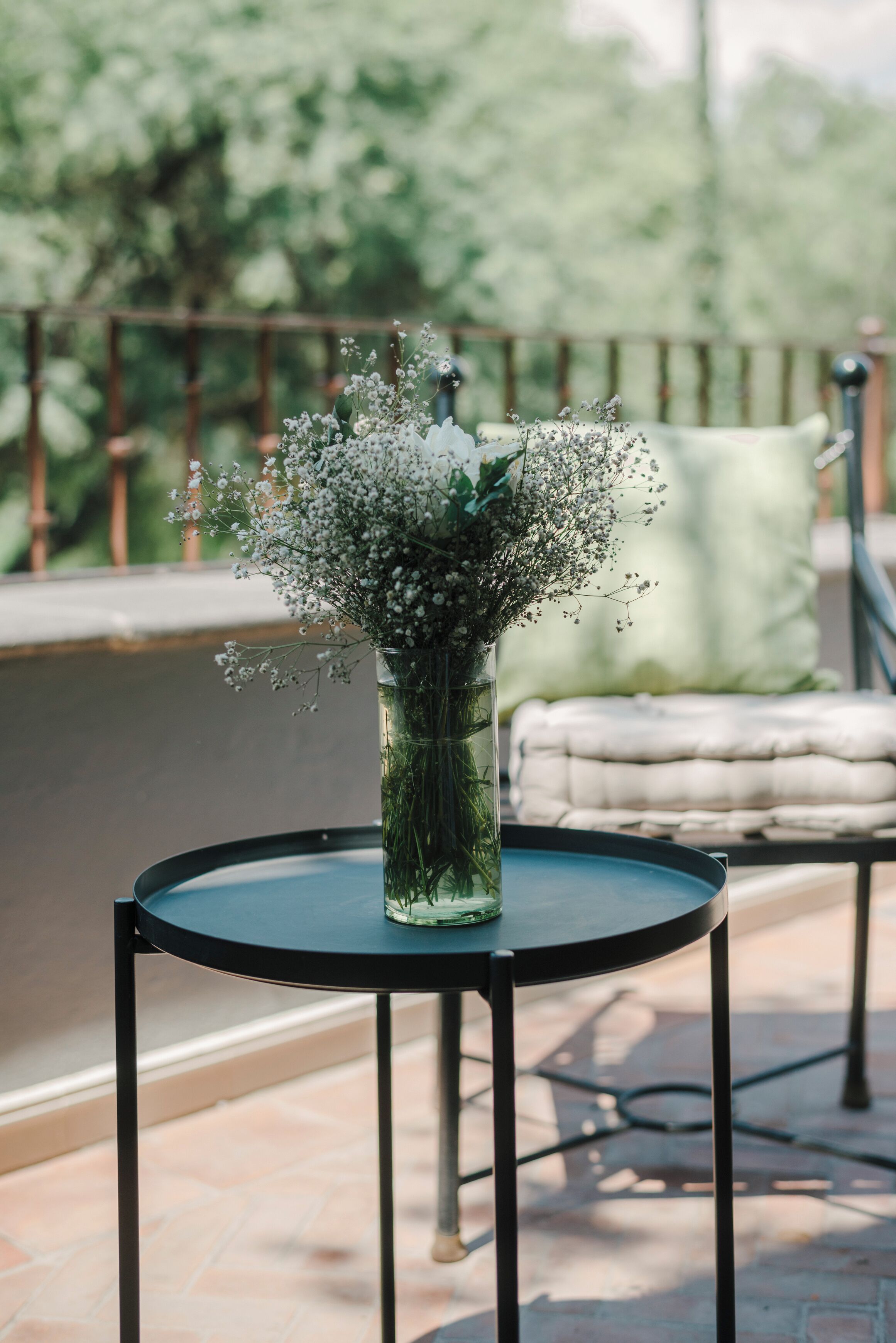 A round table with a vase of flowers on a balcony.