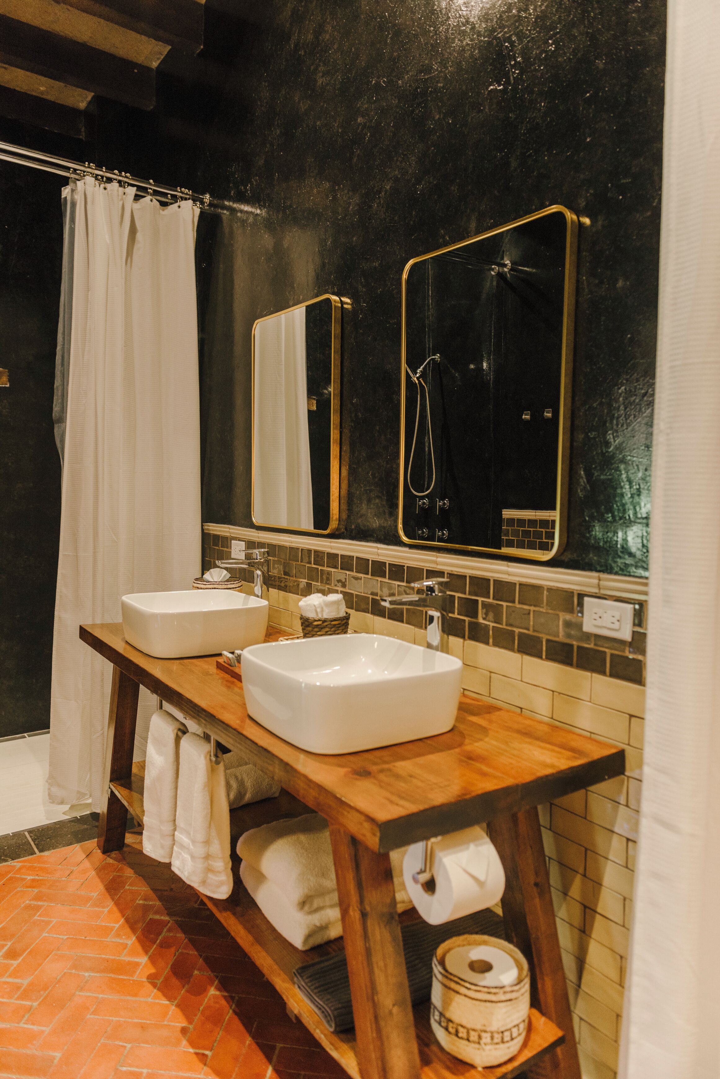 A bathroom with two sinks, a wooden vanity, a towel rack, and a shower area.