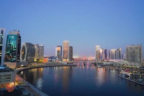 A cityscape with modern buildings, a river, and a bridge. - Magnificent 3 BR Canal Views (Dubai)