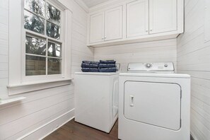 A laundry room with white cabinets and a washing machine.