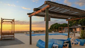 A poolside area with a pergola, lounge chairs, and a bench. - Monte Sardinha (Santiago do Cacém)