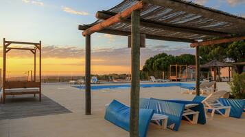 Een buitenzwembad, ligstoelen bij het zwembad