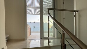 Una escalera con barandillas de cristal que lleva a una puerta con vista al mar.