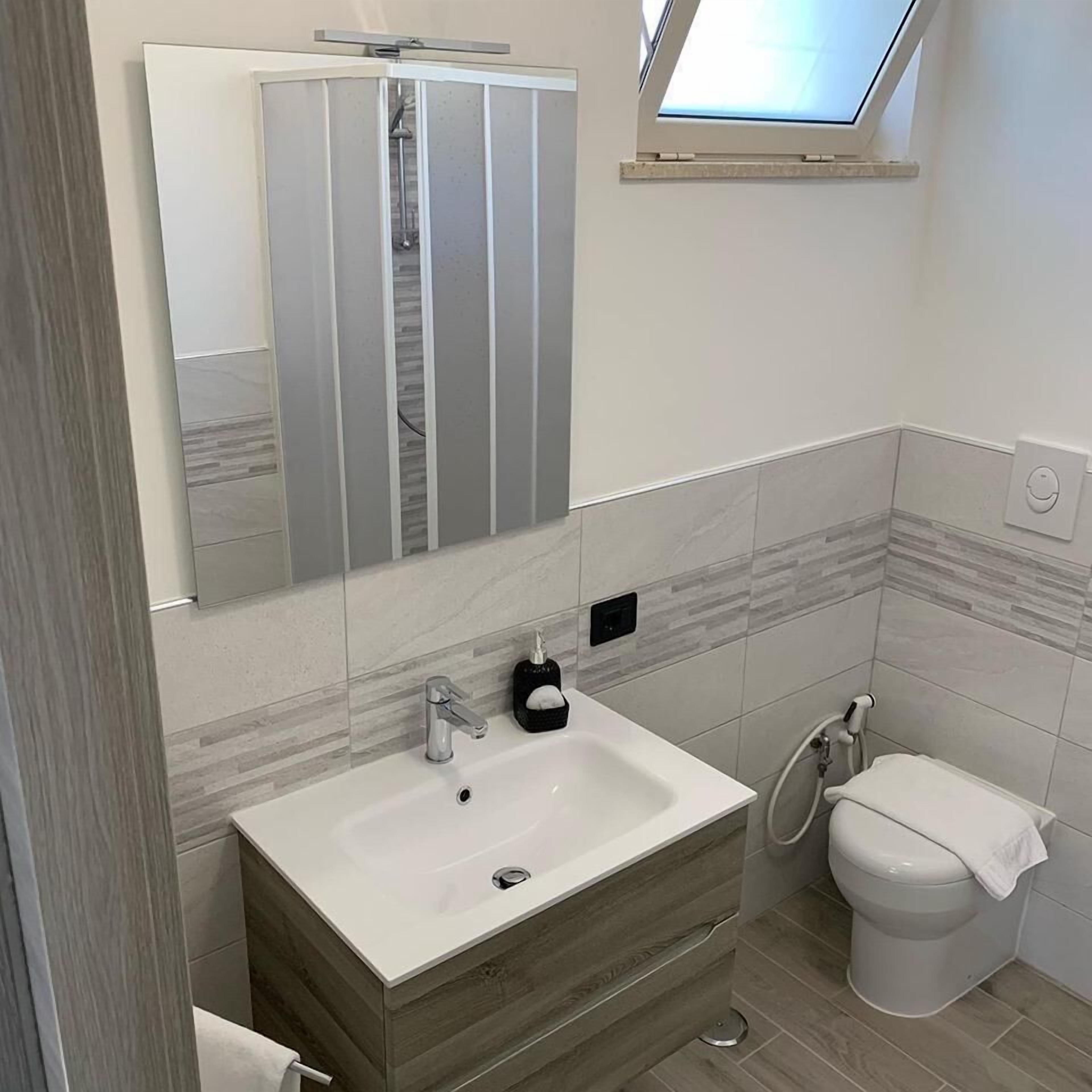 Un bagno moderno con un mobile lavabo, uno specchio e un water.