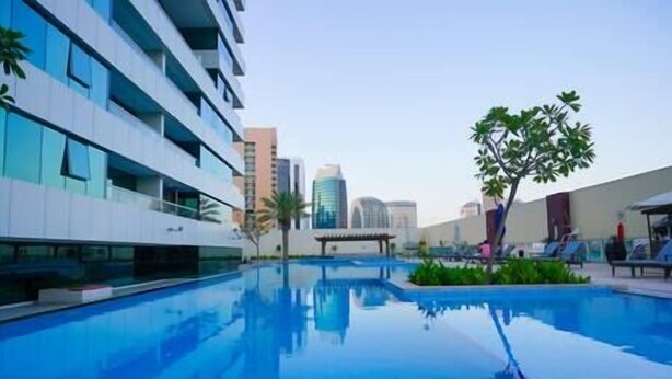A modern hotel with a swimming pool, reflecting nearby buildings. - Splendid1BRapartmentinCanalViews (Dubai)