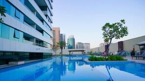 A modern hotel with a swimming pool, reflecting nearby buildings. - Splendid1BRapartmentinCanalViews (Dubai)