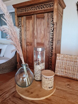 A wooden cabinet with intricate carvings, a glass vase with pampas grass, and a cylindrical container with a lid on a wooden table. - A beautiful, luxurious villa with a private pool and stunning views (Dénia)