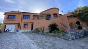 A two-story house with a stone facade, multiple windows, and a curved staircase leading to the entrance. - Pretty, luxurious villa with private pool and superb view (Dénia)